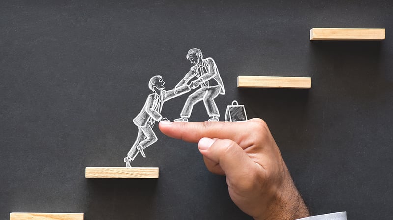 Two chalf figures climbing up stairs with a human hand making a step of the stairs.